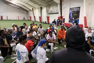 High school athletes huddled around a coach at an indoor camp