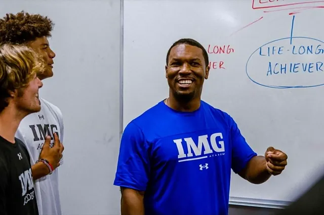 Coach Carl with student athletes at IMG Academy in Florida, in front of a whiteboard reading life-long achiever
