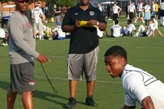 A coach running a defensive back drill with a young athlete