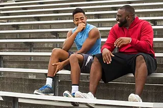 Coach Johnson of Next Level and Beyond talking with an athlete on the bleachers