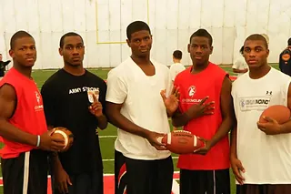 Young athletes at an indoor combine holding footballs