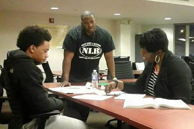 Next Level and Beyond student CJ Turner working through paperwork with a mentor and a school counselor