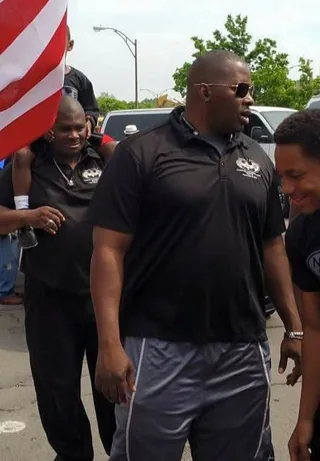 Next Level and Beyond coaches walking together at a community event behind an American flag