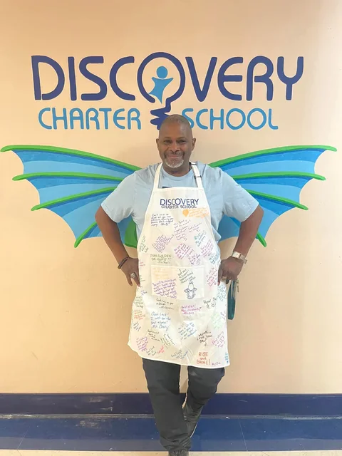 Coach Rick wearing a send off apron signed by the staff at Discovery Charter School
