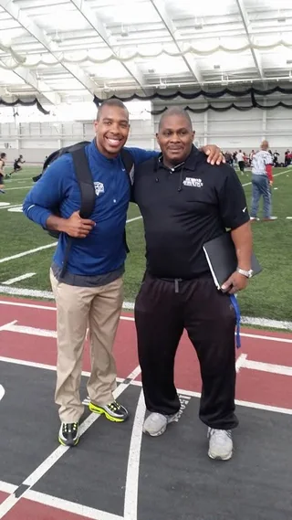 Coach Rick with a young coach at an indoor training facility, clipboard under his arm