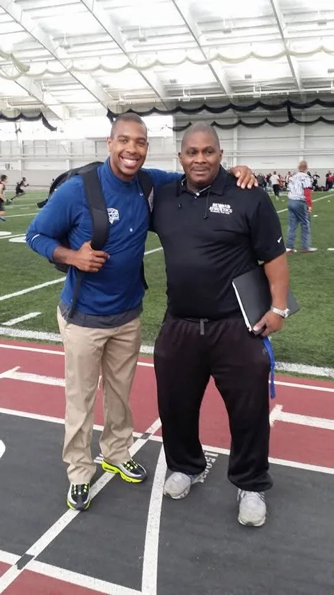 Coach Rick with a young coach at an indoor training facility, clipboard under his arm