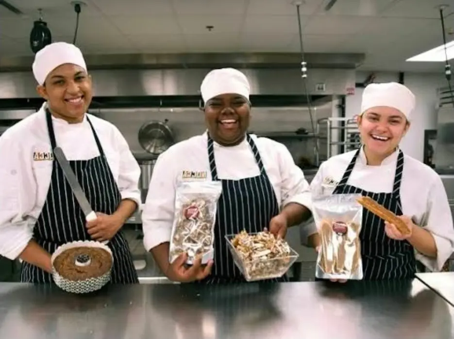 Culinary arts students in chef whites presenting dishes they made
